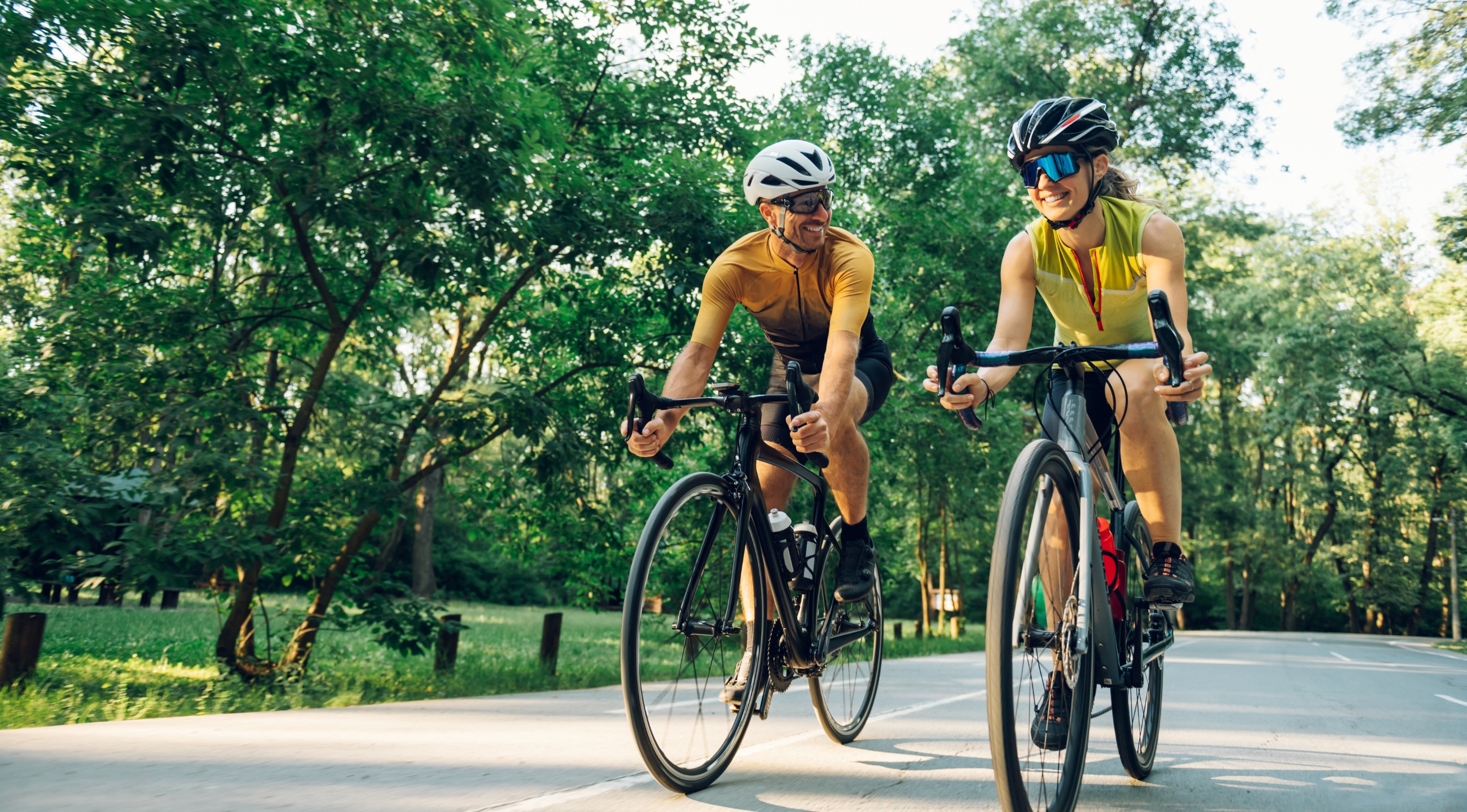 Two people riding bikes outdoors.