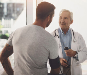 Male Provider taking vitals of a Male Patient in an exam room