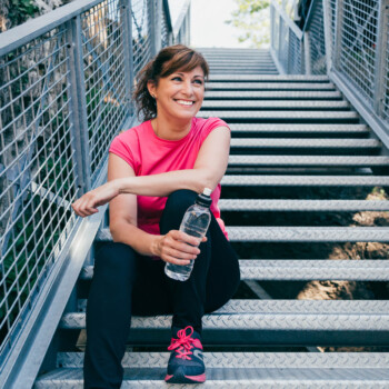 fit middle age woman sitting on stairs after exercising