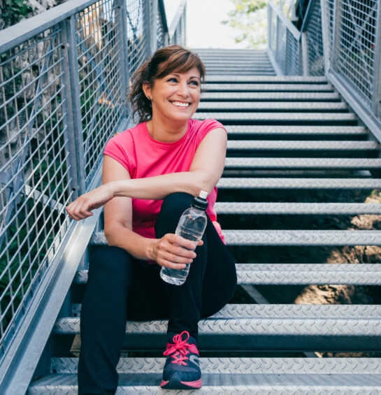 fit middle age woman sitting on stairs after exercising