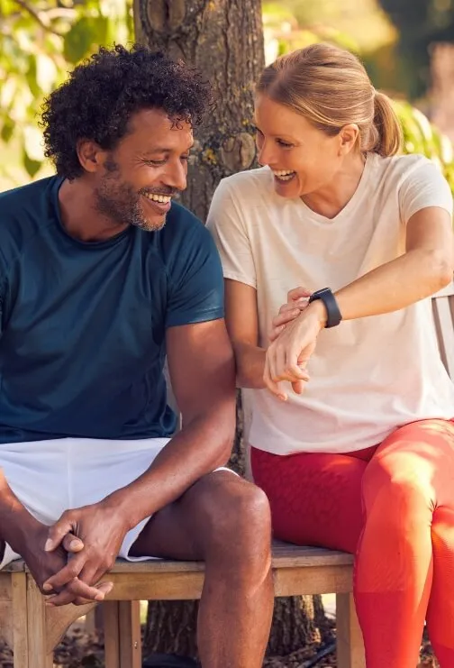 Woman and man sitting on a bench while she touches her watch.