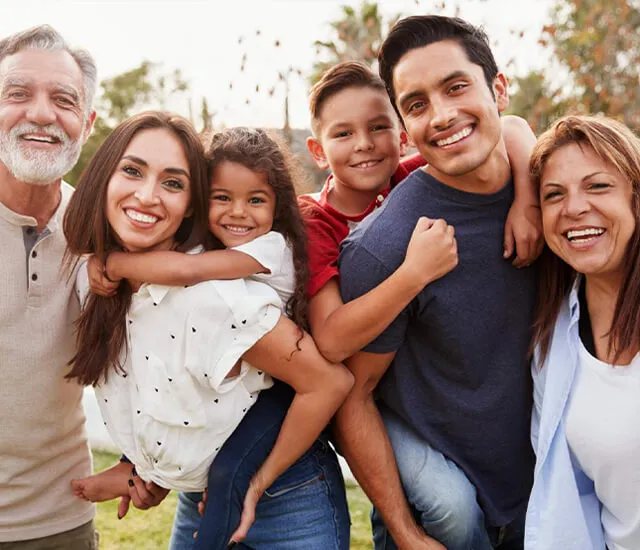 A family of six happy people in a field looking at the camera.