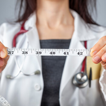 Doctor holding a tape measure in front of her.